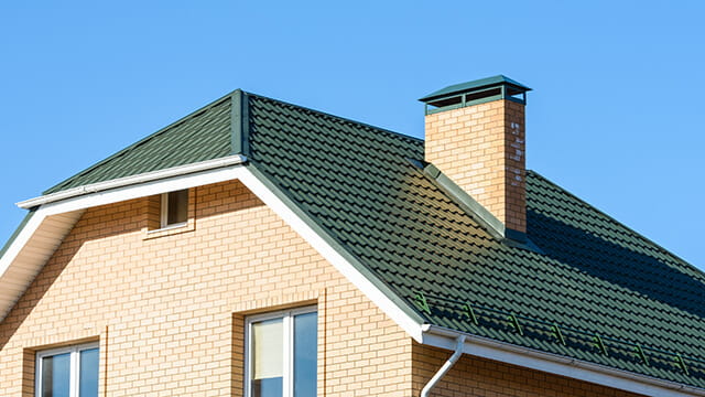 Зеленая крыша частного дома из металлической черепицы